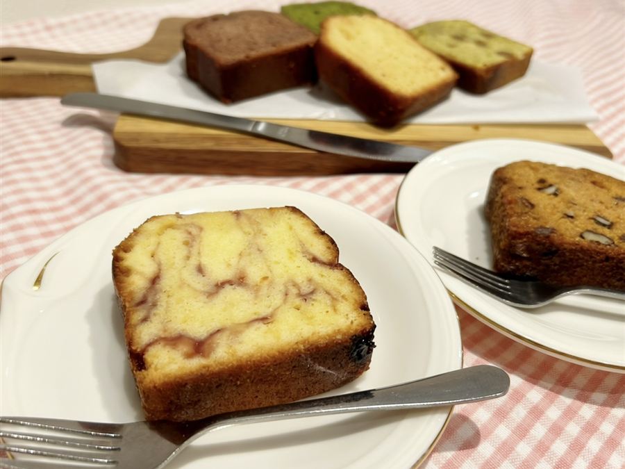 お皿にのせたパウンドケーキ。奥に、いろいろな味のパウンドケーキが並んでいます。